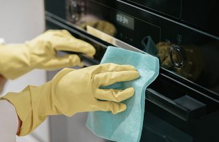 Sanering av dödsbon Händer med handskar tvättar ugn